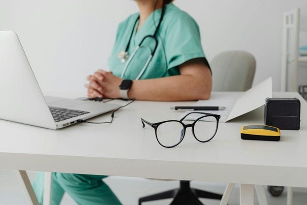 A doctors sitting on a chair in front of her table