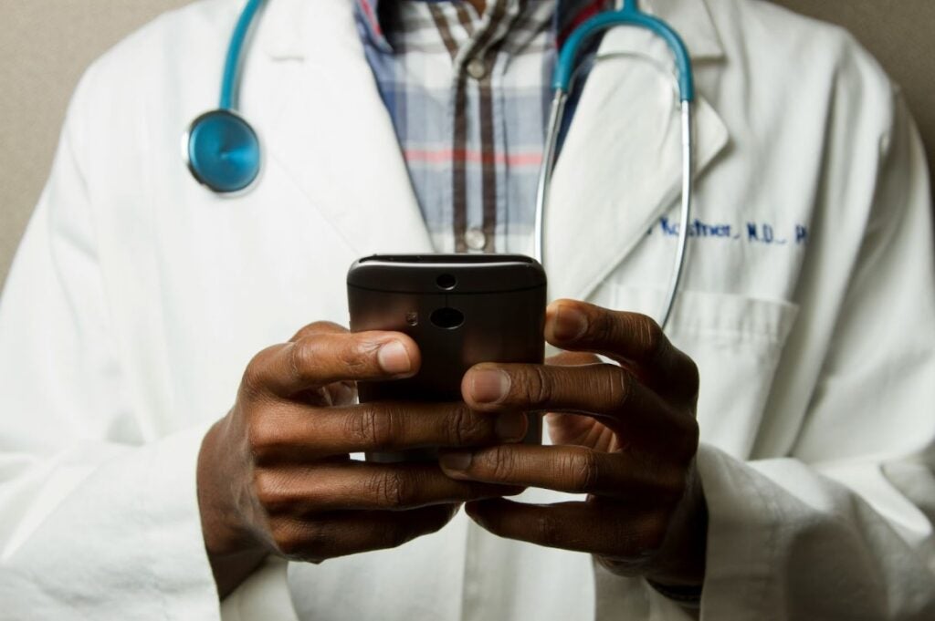 Doctor in a white coat using a smartphone.
