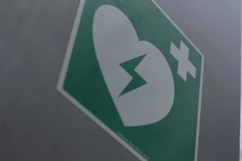 A tilted defibrillator sign on a gray surface.