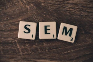 Three letter tiles on a wooden surface spelling "SEM".