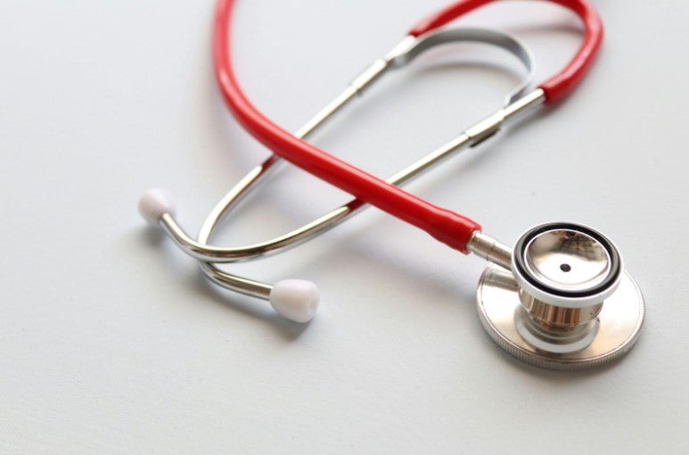 Red stethoscope on a white surface.