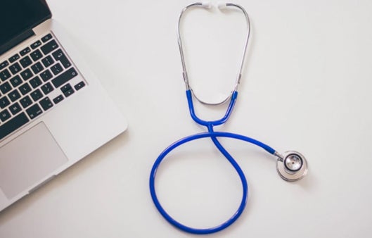 Laptop and blue stethoscope on a white background.