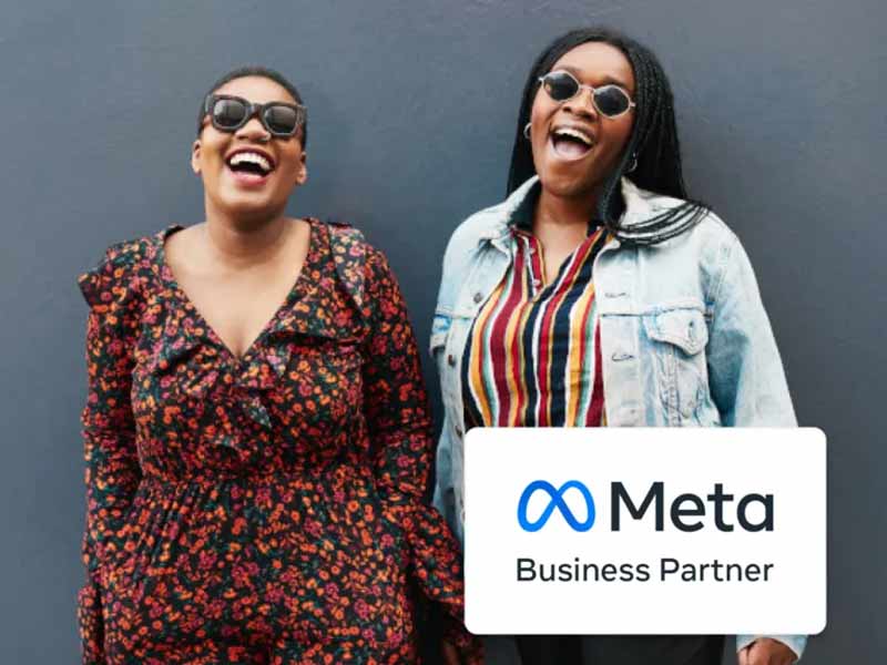 Two individuals standing beside a sign that reads "Meta Business Partner."