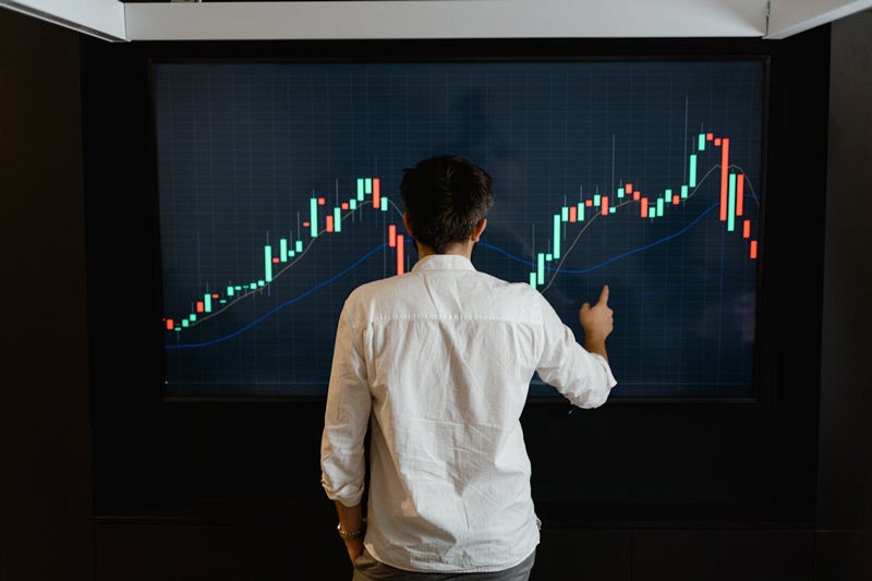 Person analyzing data on a large digital stock market chart.